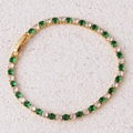 Close-up of golden tennis bracelet with inlaid green and white cubic zirconia stones - Green Bracelet-Gold
