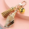 Close-up of conch shell keychain with gold bell, suede tassel and lobster clasp - Conch Tassel Bell Style