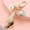 Cute cartoon conch seashell keychain with white pearl and golden accents on pink stand - Conch Pearl Shell Style