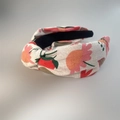 Detailansicht des handgefertigten Knotenstirnbandes mit floralem Print auf beigem Stoff - Bunte Blumen