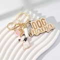 Close-up of a DOG Mama wooden charm with a white tassel and pug dog enamel keychain - White Tassel + Pug