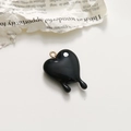 Nahaufnahme eines schwarzen schmelzenden Herzanhängers mit Goldring für DIY-Schmuck - Schwarz