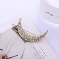 Dettaglio del fermaglio per capelli a forma di luna con strass brillanti su base dorata - Stile Zirconia / Oro