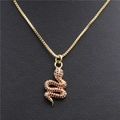 Dettaglio macro del ciondolo a serpente dorato con zirconi viola e occhi verdi su pelle - Serpente Oro con Zirconi Rosso Porpora e Occhi Verdi