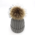 Detailed knit texture of dark grey winter hat with a fluffy brown faux fur pom pom - Gray