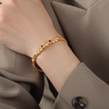 Bracciale in titanio placcato oro con cinque gemme multicolori su polso femminile - 15+5cm / Oro