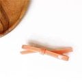 Dettaglio di un fermaglio per capelli arancione a fiocco con finitura lucida - Rosa Loto