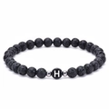 Macro detail of natural lava stone beads and white letter H charm on elastic bracelet - Letter H