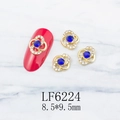Detailed macro view of 8.5x9.5mm gold hollow flower nail charm with blue gemstone inlay - Gold Flower With Blue Stone (6224)