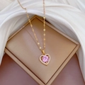 Detailed macro of a gold-plated heart pendant with a pink stone and white zircon border - Pink (G512)