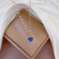 Detailed view of heart-shaped blue gemstone necklace with white diamonds on silk background - Blue (G513)