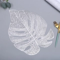 Detail of silver monstera leaf placemat with intricate hollowed veins on grey surface - 38cm / Silver