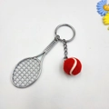 Detailaufnahme eines silbernen Tennisschlägers und eines roten Filzball-Anhängers - Rot
