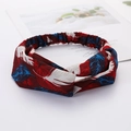 Crossed fabric headband featuring red, white, and blue leaf patterns on a white desk - Feather Style 2 Red