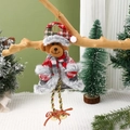 Dettaglio dell'orso natalizio in peluche con cappello scozzese e campanelli su un ramo - Orso
