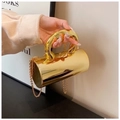 Close-up of golden cylindrical evening clutch with mirror finish and thick curved handle - Gold