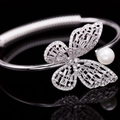 Detailed view of silver butterfly bangle with sparkling zircons and a white pearl accent - Silver