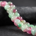 Polished 10mm green and red round agate beads with natural stone texture on black rock - New Purple Green