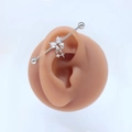 Detail eines silbernen Industrial-Piercings mit Schmetterlingsbogen und Sternanhänger - Stil #10 Schleife Stern Anhänger