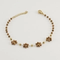 Golden bracelet with five crystal flower charms and lobster clasp on white background - Bracelet / Bronze