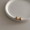 Macro detail of oval gold-plated bean earrings on a white ceramic display tray - Style 2167 / Gold
