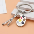 Artistic palette keychain with colorful paint and metal brush pendants on a pink background - Silver