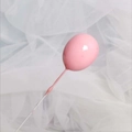 Detail eines rosa ballonförmigen Tortenaufsatzes mit glatter Oberfläche auf Tüll-Hintergrund - Rosa