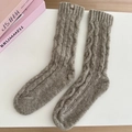 Detail of cable knit wool socks in brown with a small leather brand patch on top - One Size / Oatmeal Khaki