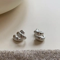 Dettaglio macro di orecchini a goccia in metallo argento lucido su tessuto tweed - Argento