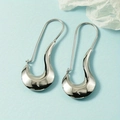 Elegant silver irregular fluid U-shaped metallic earrings on a fresh blue background - White Gold