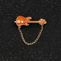 Dettaglio spilla a forma di chitarra arancione con catena d'oro su fondo nero - Chitarra Arancione Oro Con Catena