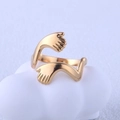 Detailaufnahme eines goldfarbenen Edelstahlrings in Handform auf weißem Dekor - Gold / Einstellbar Offen