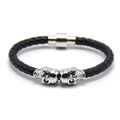 Dettaglio del bracciale in pelle nera intrecciata con teschi argentati e chiusura magnetica - Bianco K + Pelle Nera