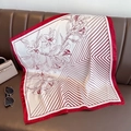Eleganter rot-weißer Seidenschal mit Blumenmuster auf einem Sofa mit Accessoires - Rot