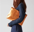 Macro shot of metallic orange glitter envelope clutch with secure top metal zipper closure - Orange
