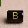Macro detail of a black rectangular bead with a gold letter B for DIY jewelry making - Letter B
