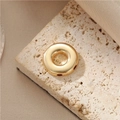 Polished gold donut-shaped metal jewelry pendant accessory displayed on a beige stone - 14K Gold D888 Donut Bead