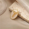 Close-up of golden oval shell pendant featuring a 3D flower relief on silk background - 14K Gold H-10001 Shell Flower Pendant