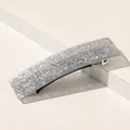 Vue détaillée d'une pince à cheveux carrée argentée scintillante sur socle - Argent Pailleté