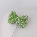 Macro detail of a green rhinestone bowknot charm with sparkling crystals on a silver pin - Light Green AB