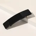 Gros plan d'une pince à cheveux rectangulaire noire brillante avec un ressort en métal - Noir