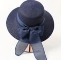 Detailed view of dark blue woven straw hat with large translucent mesh bow on a metal stand - Adjustable / Navy Blue