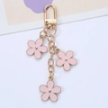 Colorful floral alloy keychain with three pink flower charms and golden chain on white background - Pink