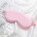 Pink silk texture sleep mask with elastic strap shown on white fabric and pearls - No. 4 Pink Eye Mask