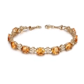 Elegante bracciale dorato con gemme arancioni ovali e accenti a forma di quadrifoglio - Bracciale