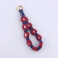 Detail of handmade woven cotton daisy lanyard with navy blue and red patterns and gold ring - Red