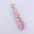 Macro view of hand-woven daisy floral keychain with pink cotton cord and gold spring ring - Pink Gray