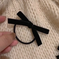Elegante goma para el pelo con lazo de terciopelo negro sobre fondo de punto beige - Estilo de Coletero