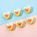 Close-up of yellow and orange heart beads for DIY crafts on a blue and pink background - Yellow