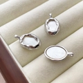 Close-up of three irregular oval silver pendants with white mother of pearl inlay - Silver Plated Border White Shell